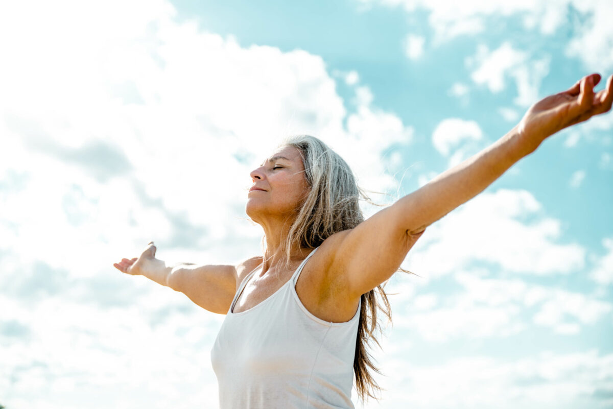 Joyful senior woman enjoying freedom standing with open arms and